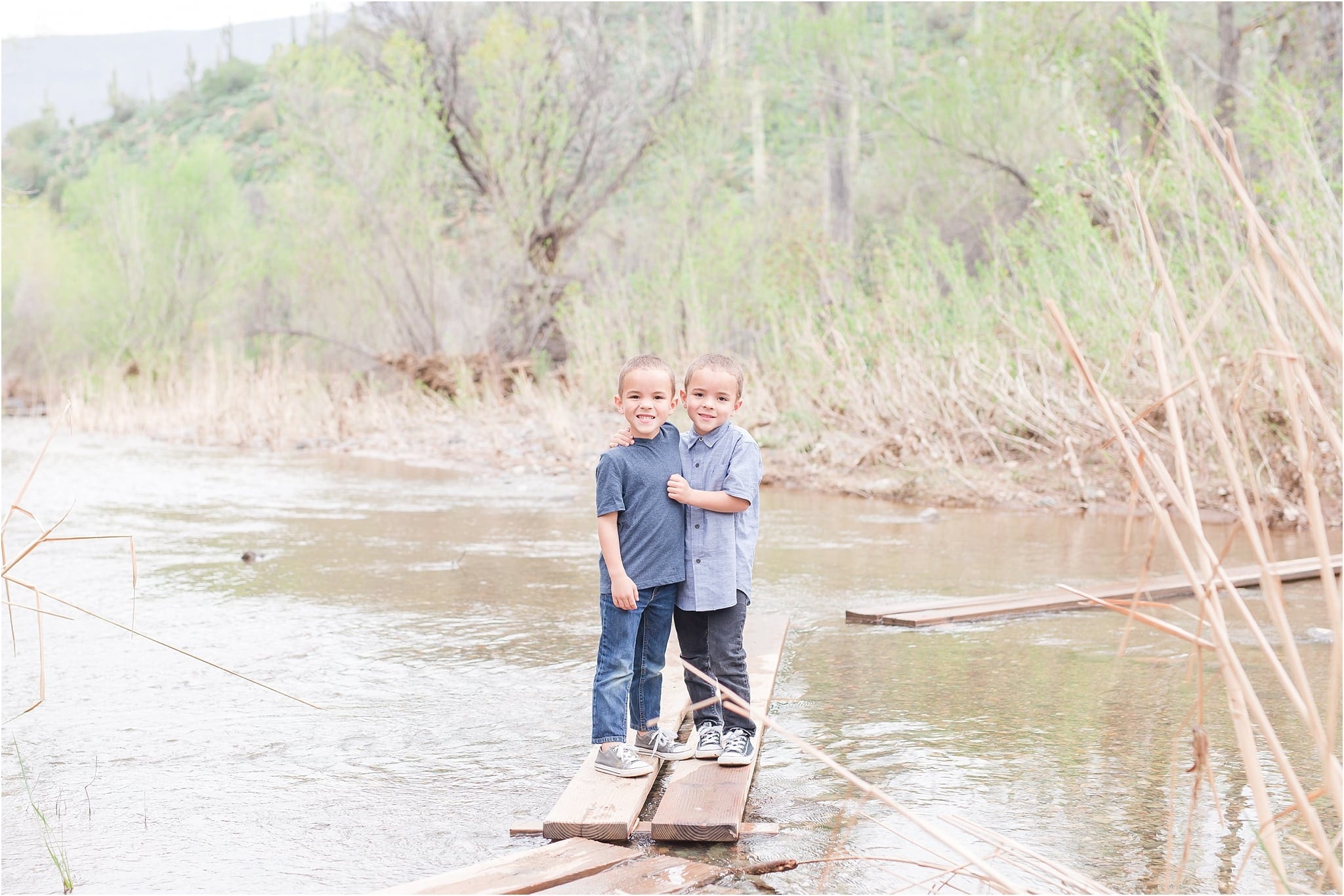 Twin boys standing on wood in creek