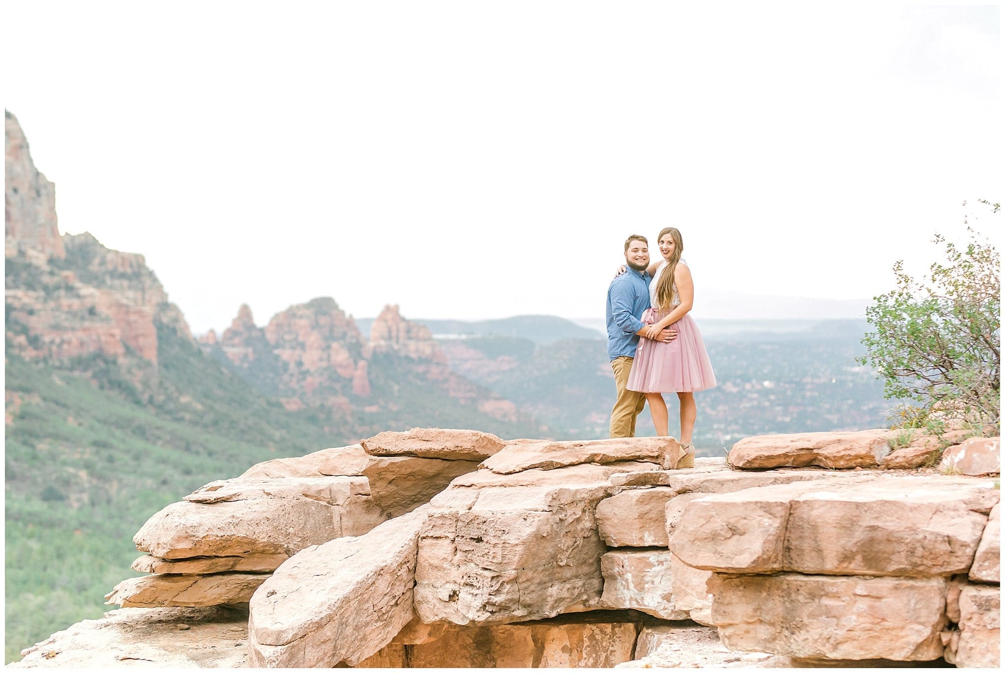couple holding hands on top of red rock