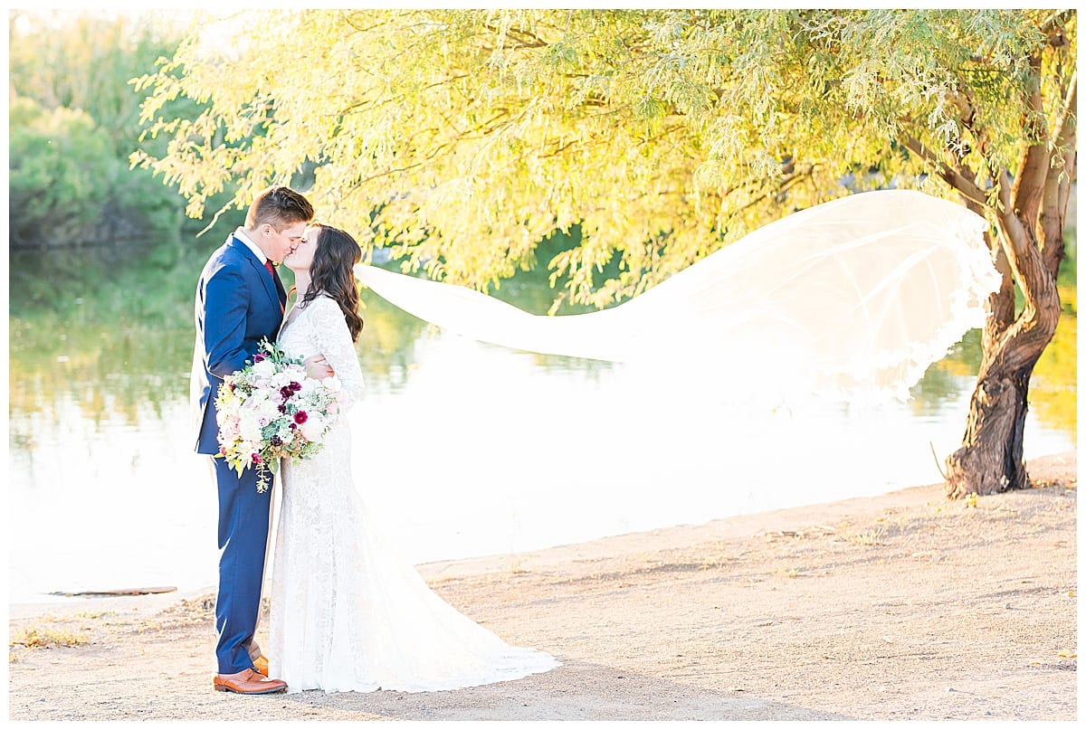 veil floating in wind by lake, couple kissing