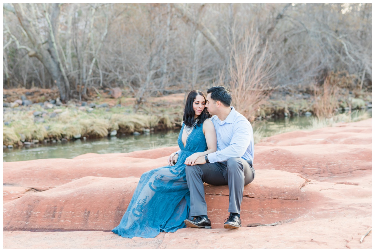 couple sitting on red rock, blue dress, blue shirt, grey pants