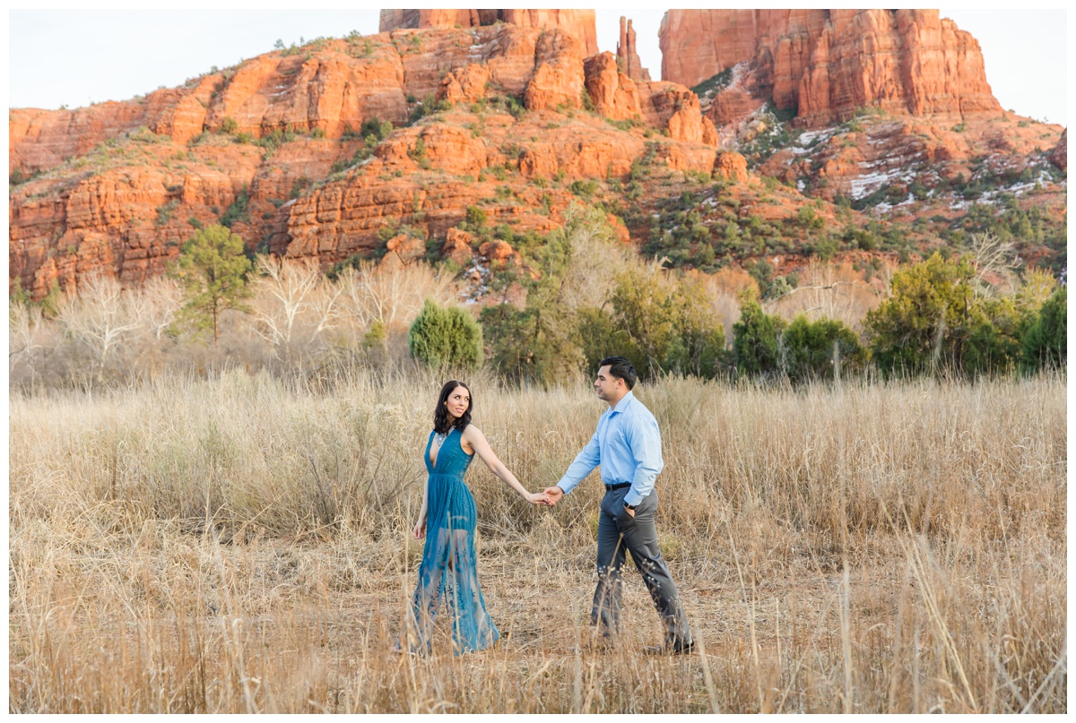 couple walking in front of cathedral rock holding hands